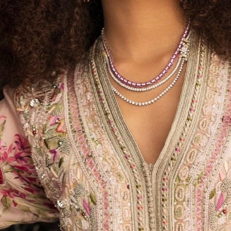 Blush floral Moroccan kaftan with a hand-embroidered placket, seen close against dark marble